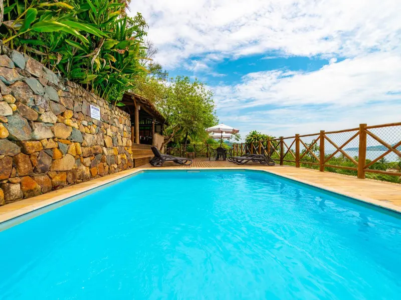 Une piscine turquoise bordée d'une terrasse en bois avec des chaises longues.