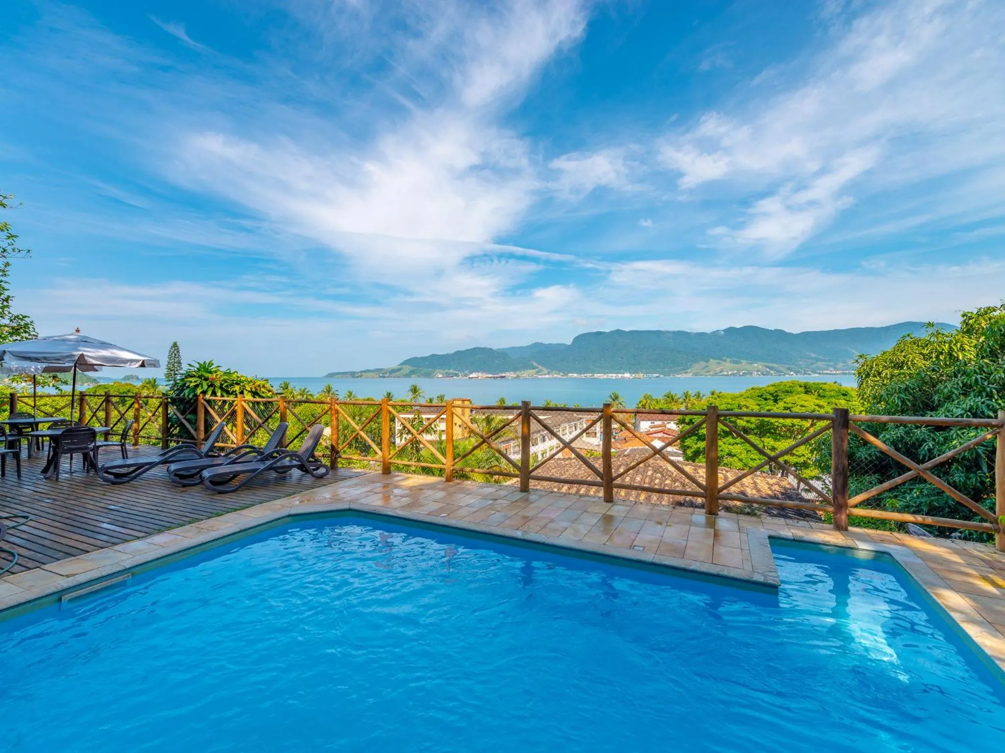 Terrasse avec piscine et vue sur la mer et les montagnes.