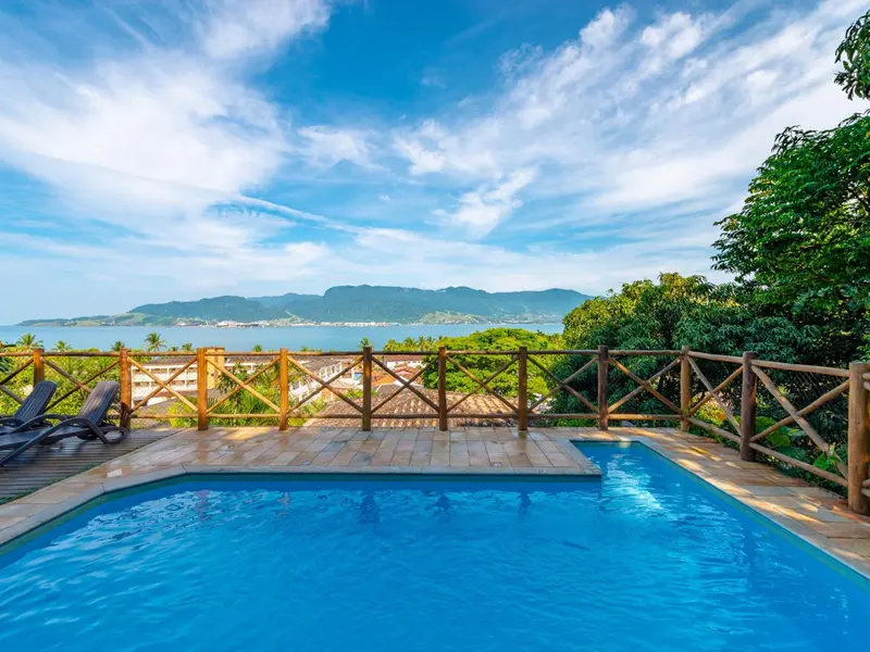 Une piscine turquoise surplombe une vue panoramique sur la mer et la côte.