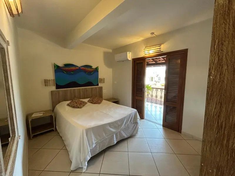 Une chambre lumineuse avec un lit double et une porte ouverte sur une terrasse.