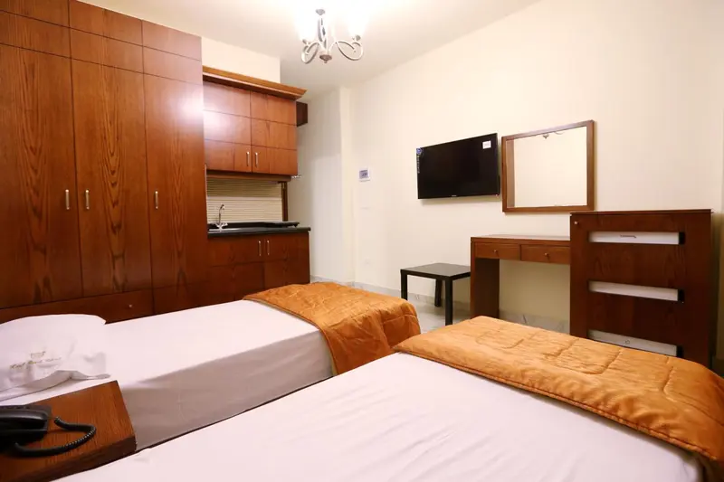 Une chambre avec deux lits et un bureau en bois.
