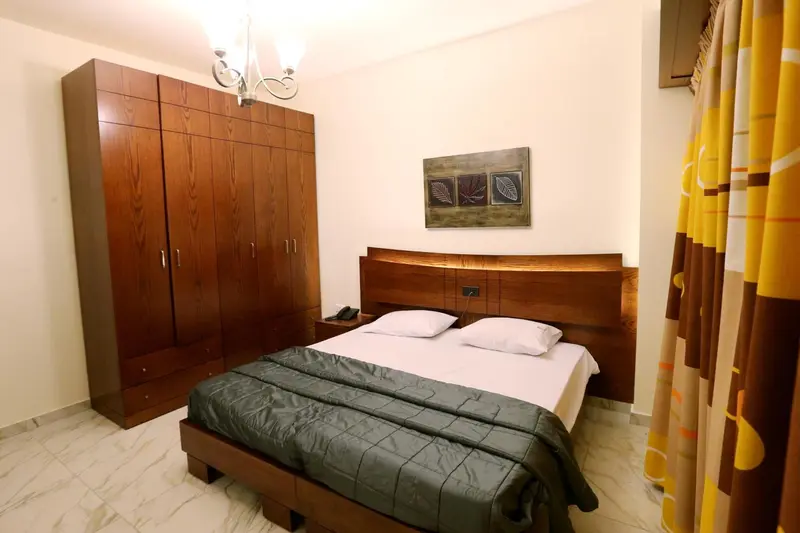 Une chambre avec un grand lit et une armoire en bois.