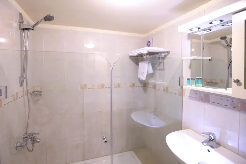 Une salle de bain lumineuse avec douche et lavabo.