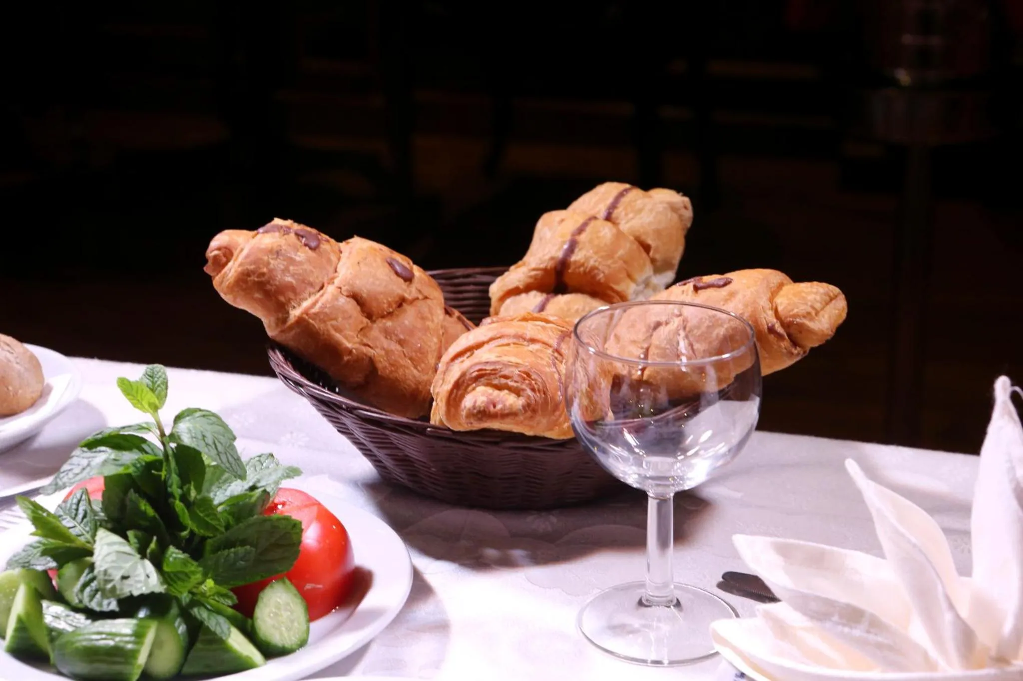 Une nature morte avec des viennoiseries, une salade et un verre d'eau.