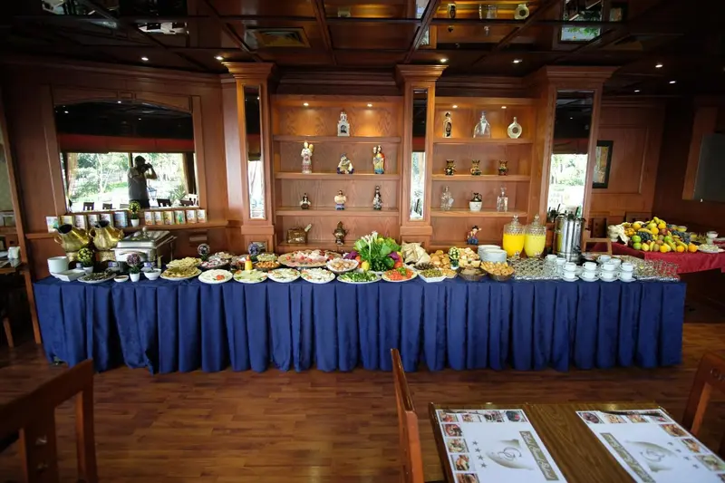 Un buffet de nourriture est présenté sur une table recouverte d'une nappe bleue dans une salle à manger en bois.