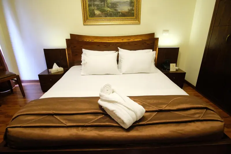 Une chambre avec un grand lit recouvert d'une courtepointe et de coussins blancs.