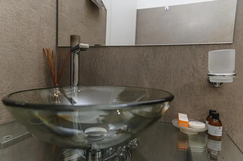 Un lavabo en verre transparent sur un meuble sombre dans une salle de bain.