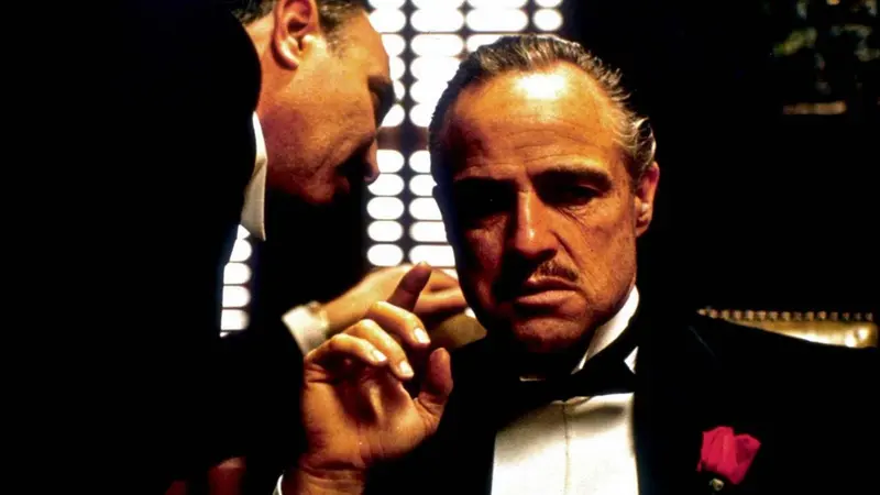 Deux hommes en smoking se regardent, l'un pointant son doigt vers l'autre.