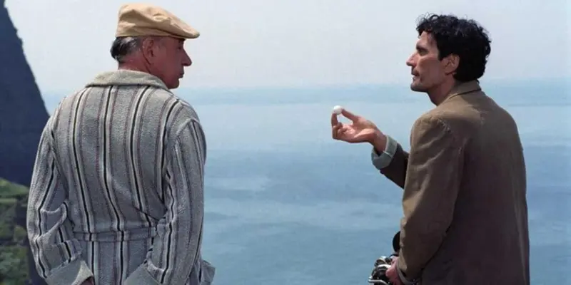 Deux hommes discutent face à la mer sur une falaise.