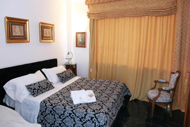 Une chambre avec un lit recouvert d'une courtepointe noire et blanche et une chaise.