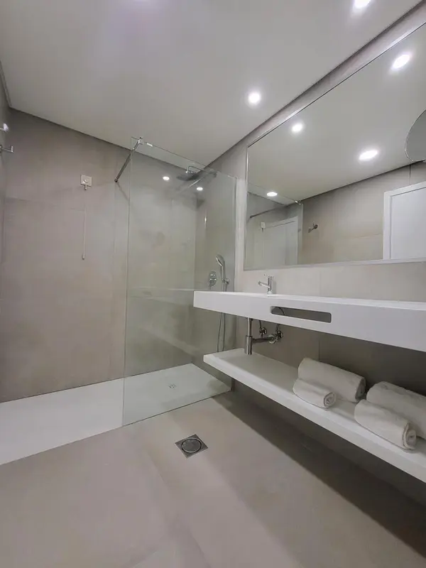 Une salle de bain moderne avec douche à l'italienne et grand miroir.