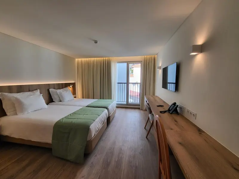 Une chambre lumineuse avec un grand lit et un accès à une terrasse.