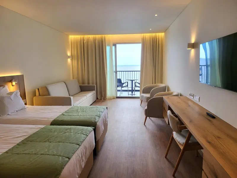 Une chambre lumineuse avec un canapé et un accès à un balcon.