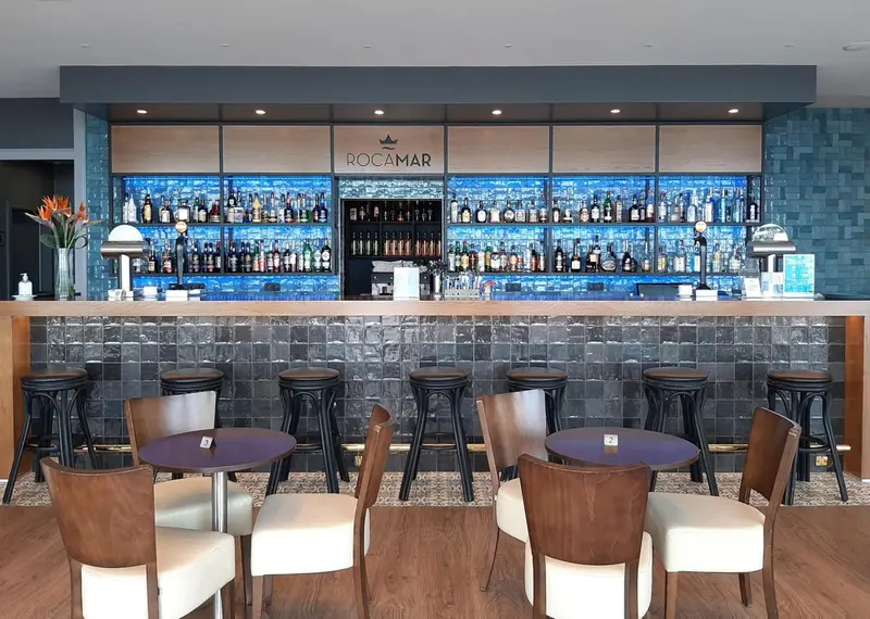 Un comptoir de bar moderne avec des tabourets et des tables.