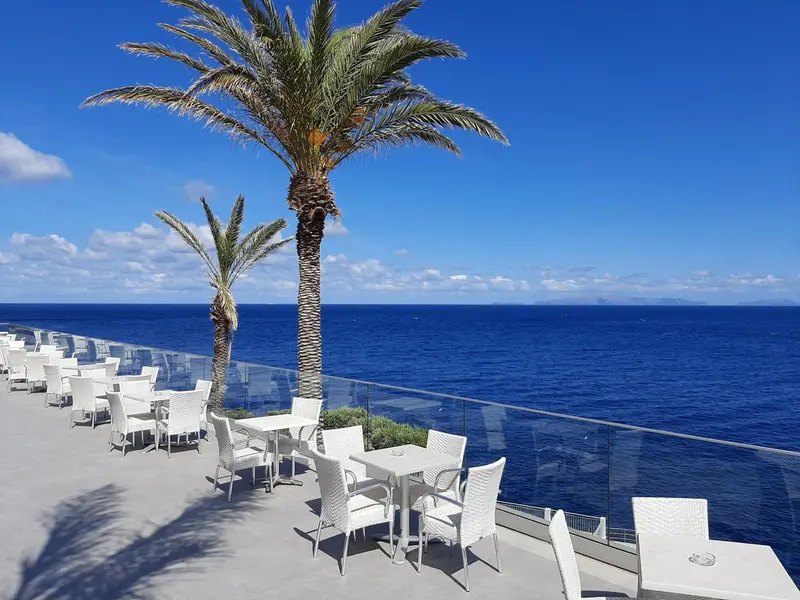 Terrasse avec tables et chaises donnant sur la mer.