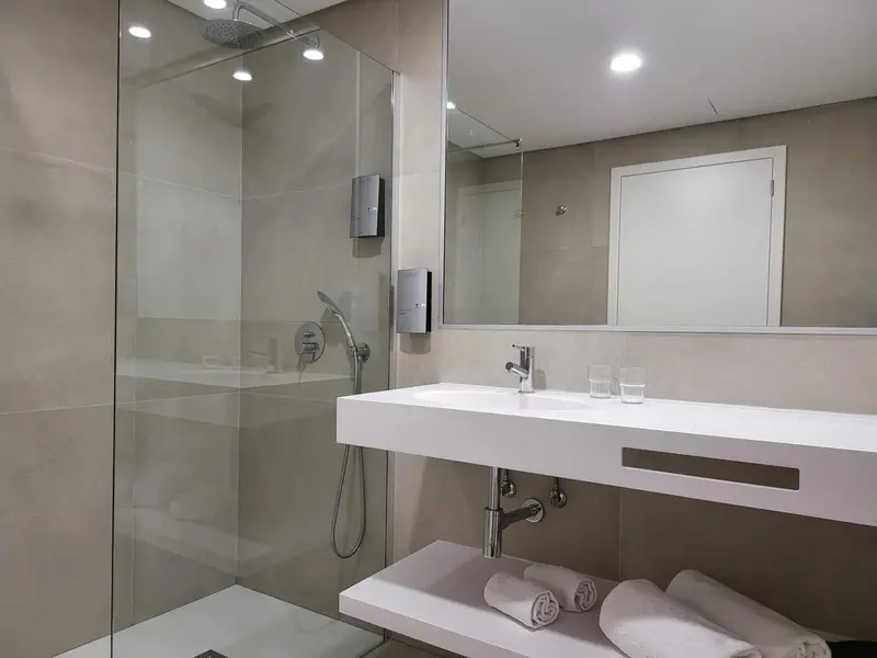 Une salle de bain moderne avec douche à l'italienne et vasque blanche.