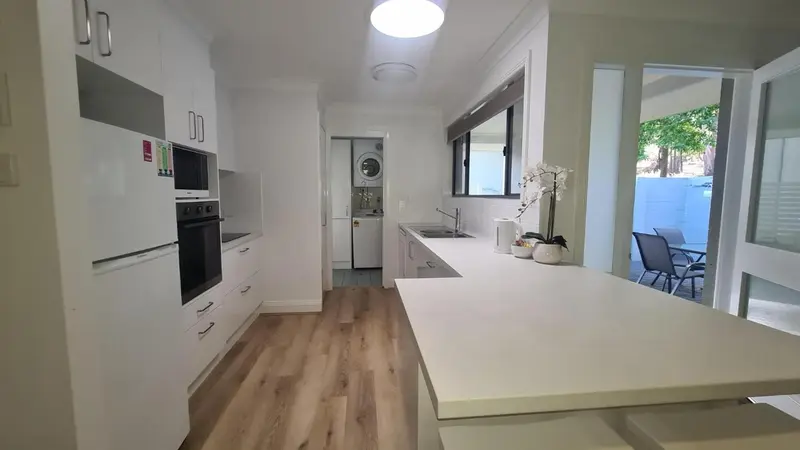 Cuisine moderne et lumineuse avec un îlot central et vue sur une terrasse.