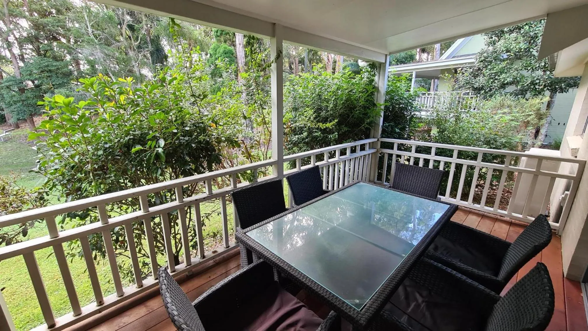 Une terrasse aménagée avec une table et des fauteuils en osier offre un espace de détente extérieur.
