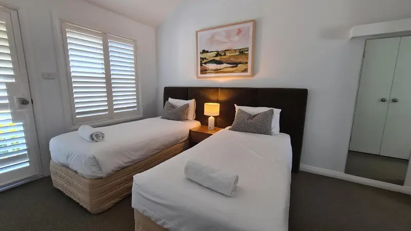Une chambre lumineuse avec deux lits simples et une décoration sobre.