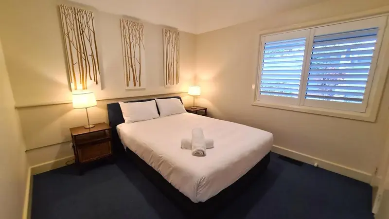 Une chambre lumineuse avec un grand lit et des rideaux en bois.