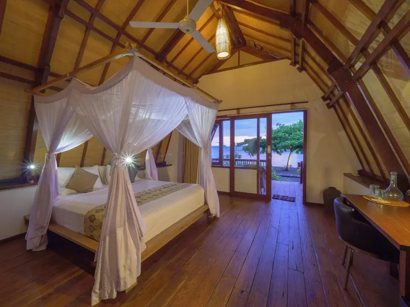 Une chambre lumineuse avec un lit à baldaquin donnant sur une vue sur la mer.