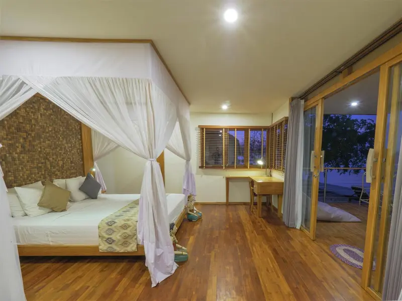 Une chambre lumineuse avec un grand lit à baldaquin et une vue sur l'extérieur.