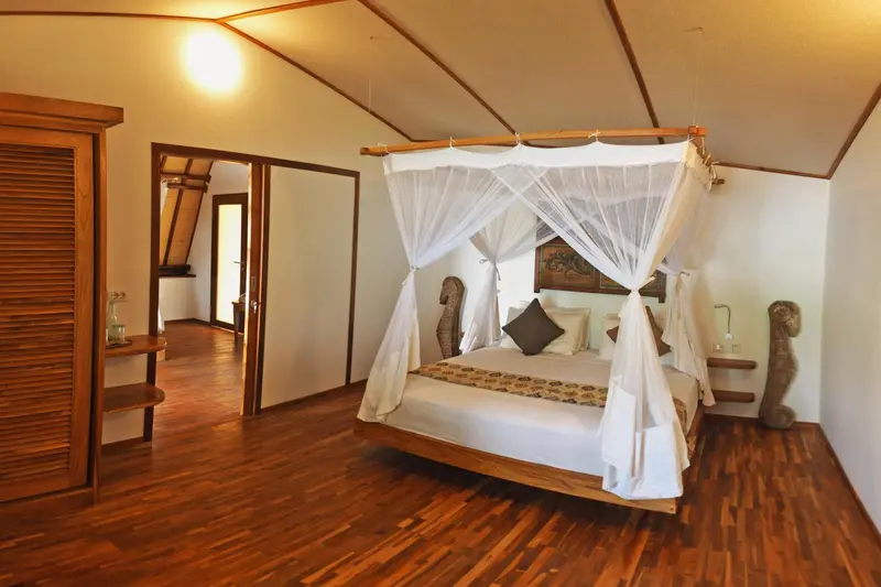Une chambre avec un lit à baldaquin et un parquet en bois.