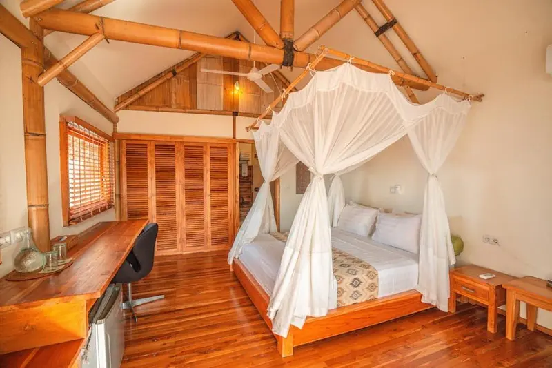 Une chambre lumineuse avec un lit à baldaquin et un bureau en bois.