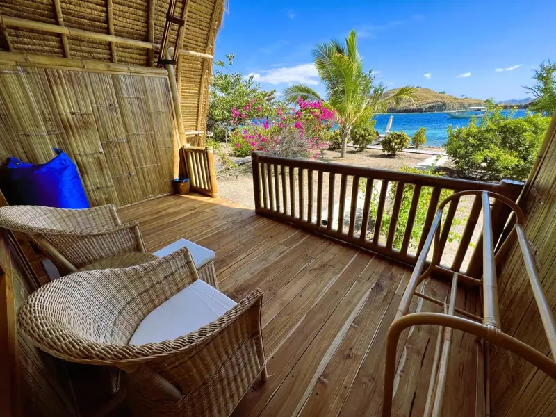 Terrasse en bois avec mobilier en rotin donnant sur une plage et la mer.