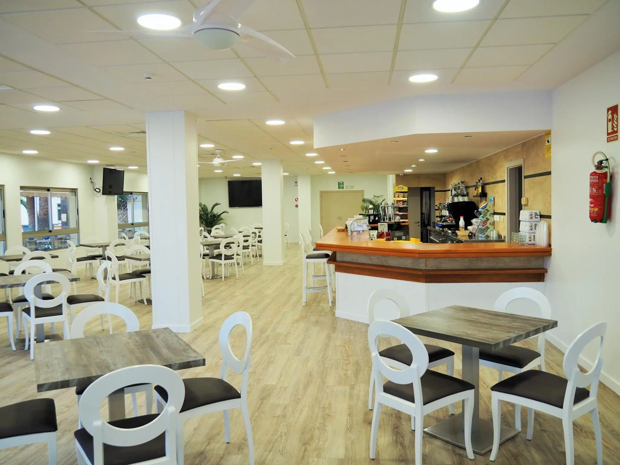 Une salle lumineuse avec des tables, des chaises et un comptoir de bar.