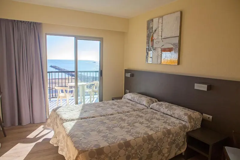 Chambre lumineuse avec un grand lit donnant sur une vue mer.