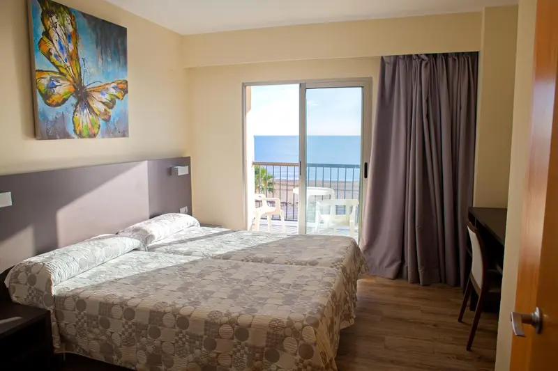 Chambre lumineuse avec un grand lit et une vue sur la mer.