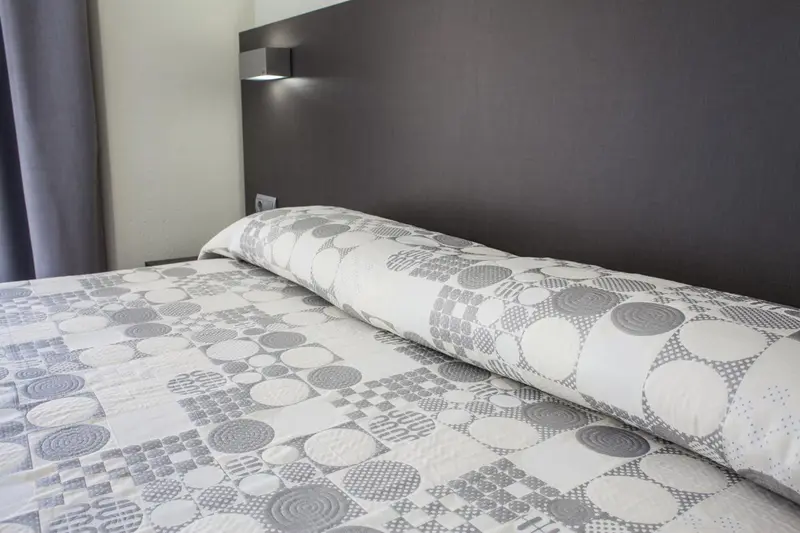 Un lit recouvert d'une couette et d'oreillers dans une chambre.