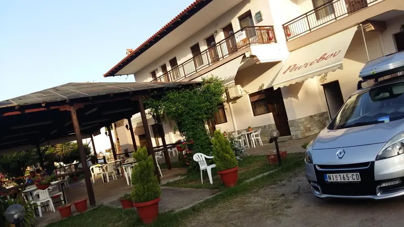 Façade d'un bâtiment avec une terrasse ombragée et des tables.