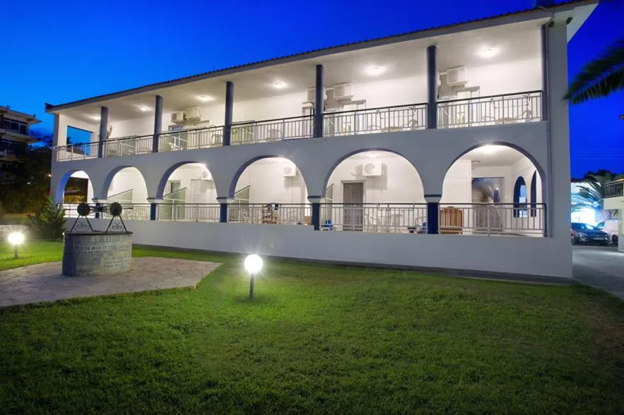 Bâtiment blanc à deux étages avec des arches et des balcons illuminés la nuit.