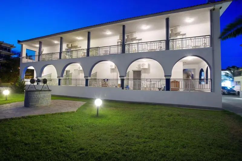 Bâtiment blanc à deux étages avec des arches et des balcons illuminés la nuit.