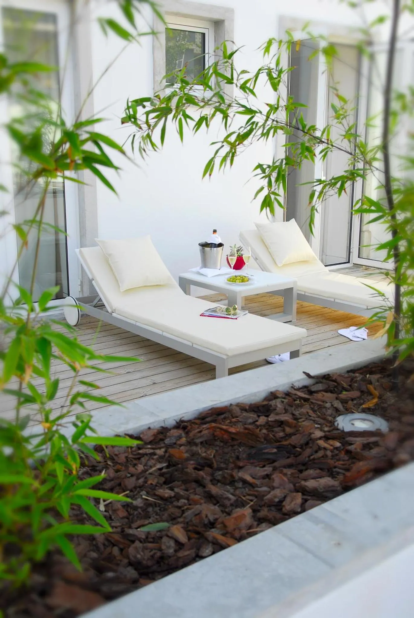 Deux transats blancs sur une terrasse en bois avec une table basse et des boissons.