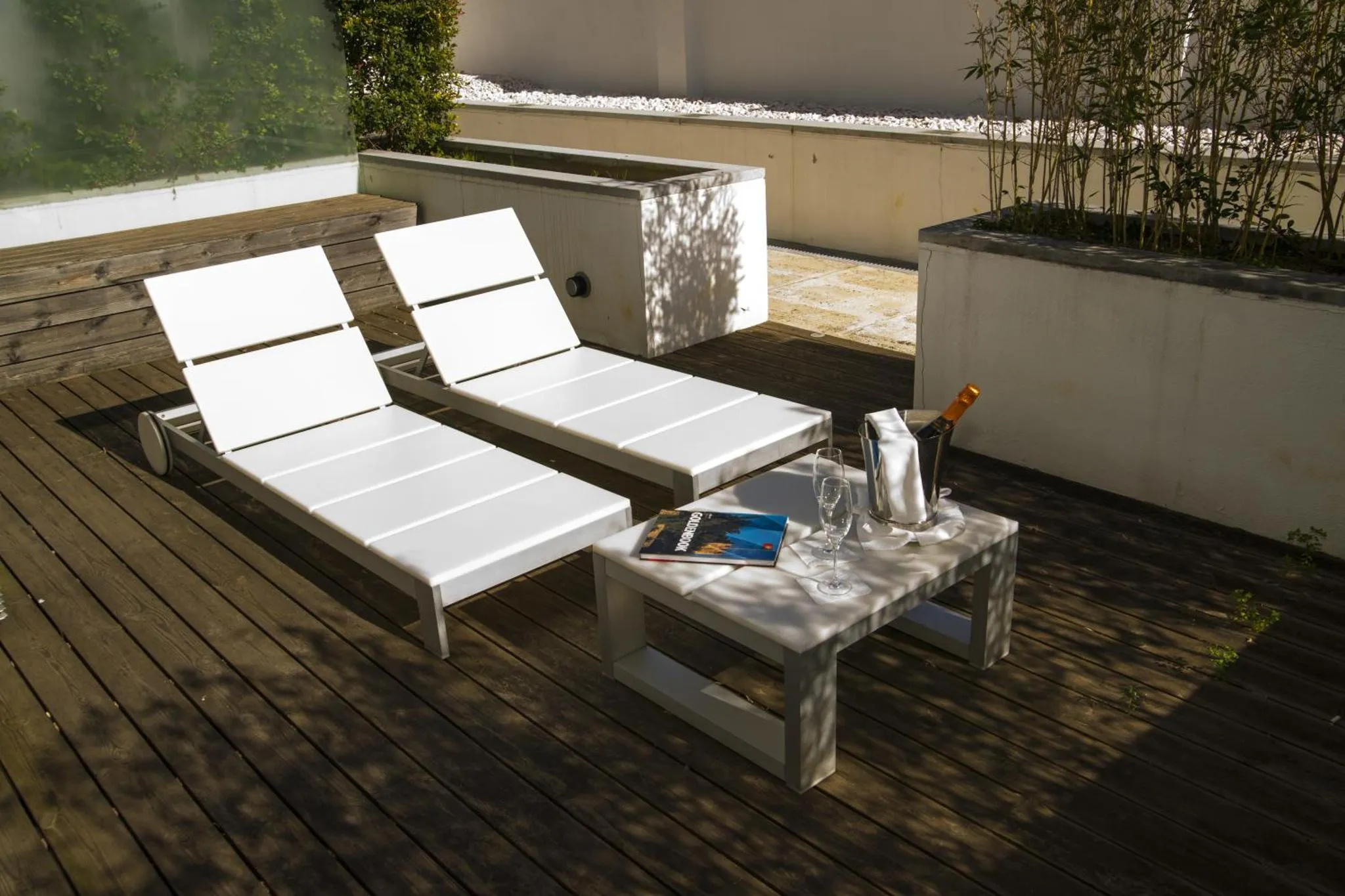 Deux transats blancs sur une terrasse en bois avec une table d'appoint.