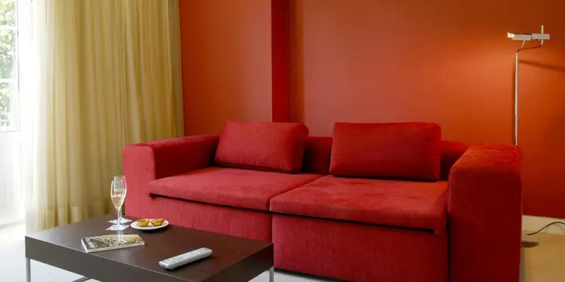 Un canapé rouge est placé devant un mur de couleur vive dans une pièce lumineuse.