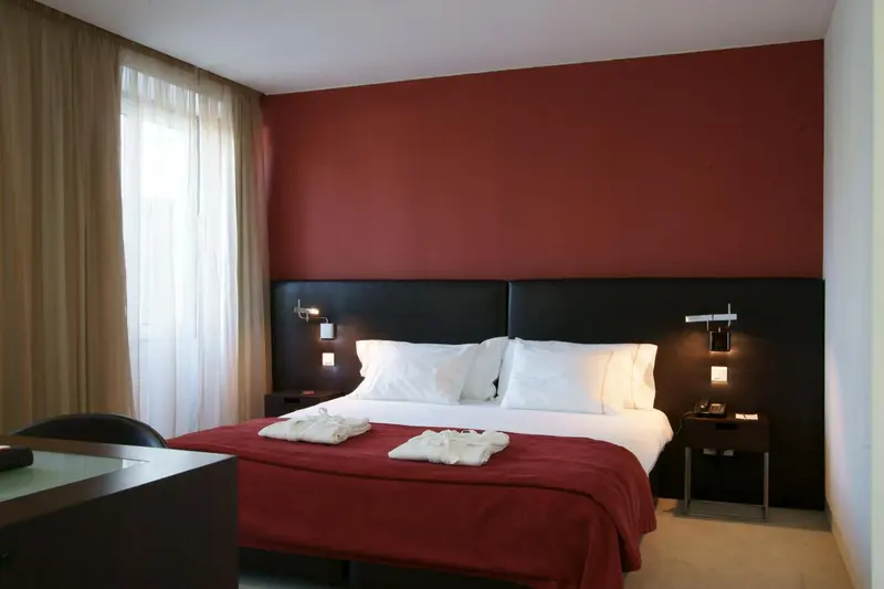 Une chambre avec un grand lit recouvert d'une couverture rouge et de coussins blancs.