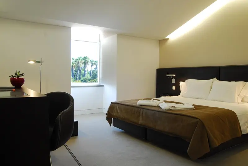 Une chambre lumineuse avec un lit et un bureau près d'une fenêtre.