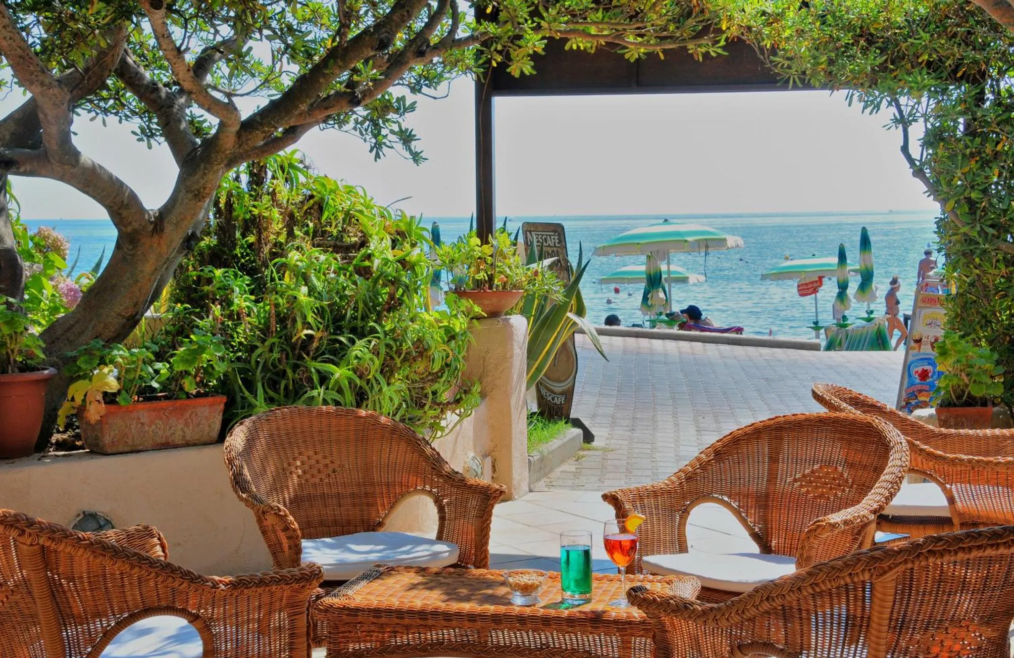 Terrasse ombragée avec mobilier en rotin et vue sur la mer.