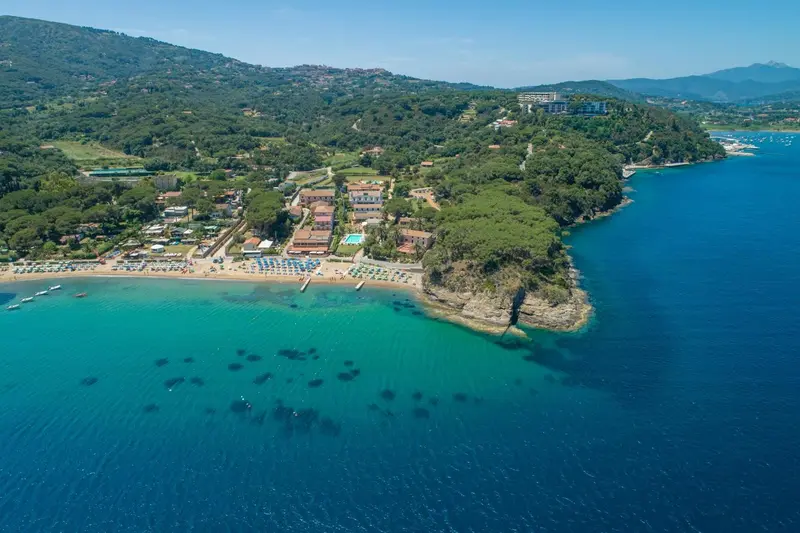 Vue aérienne d'une plage et d'un complexe hôtelier sur une côte rocheuse.