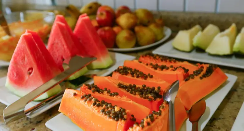 Assortiment de fruits frais coupés et présentés sur un buffet.
