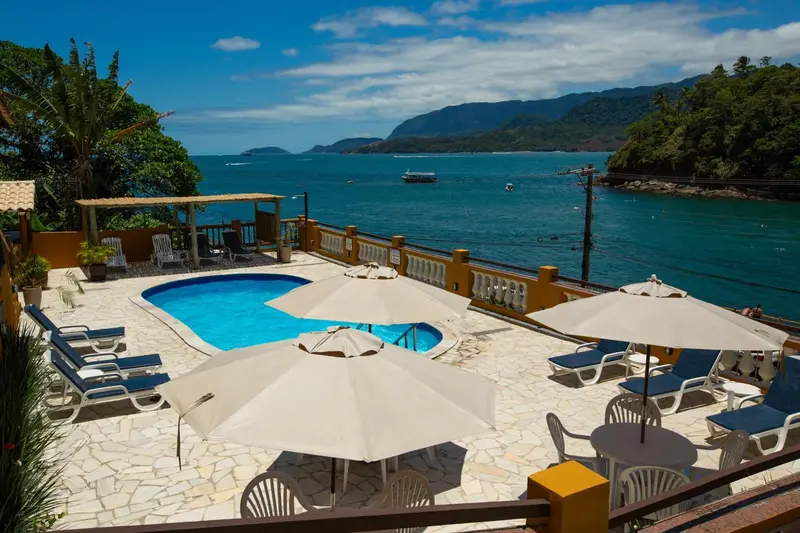 Terrasse avec piscine et transats ensoleillés face à la mer.