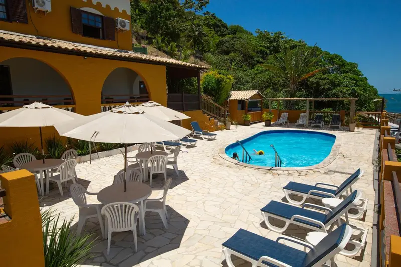 Terrasse avec parasols et chaises longues donnant sur une piscine et la mer.