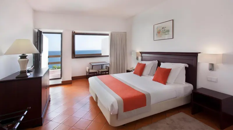 Chambre lumineuse avec un lit double et une vue sur la mer.
