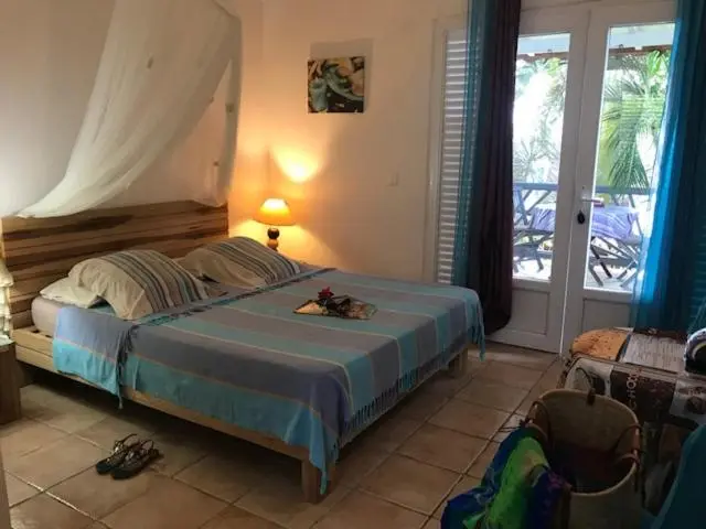 Une chambre lumineuse avec un lit à baldaquin donnant sur une terrasse.