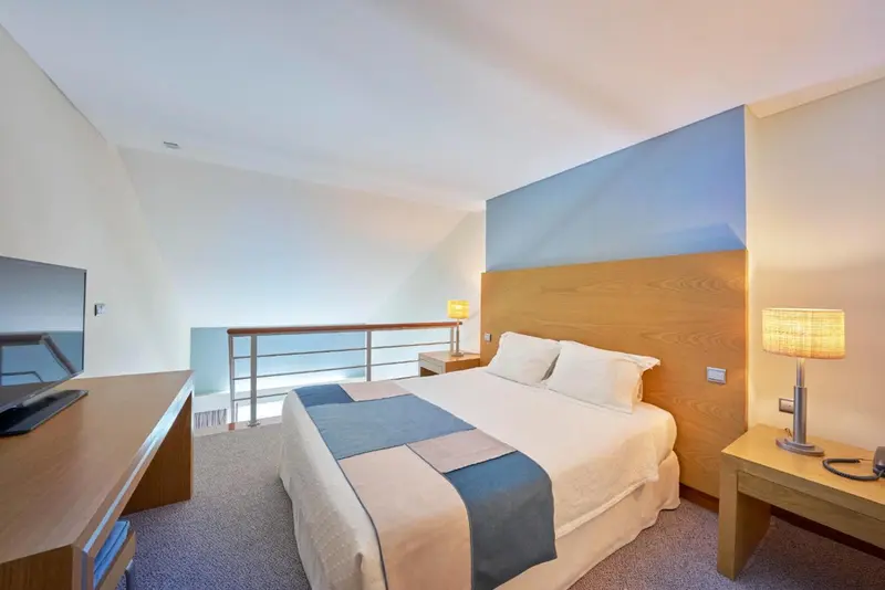 Une chambre lumineuse avec un grand lit et un espace détente surélevé.