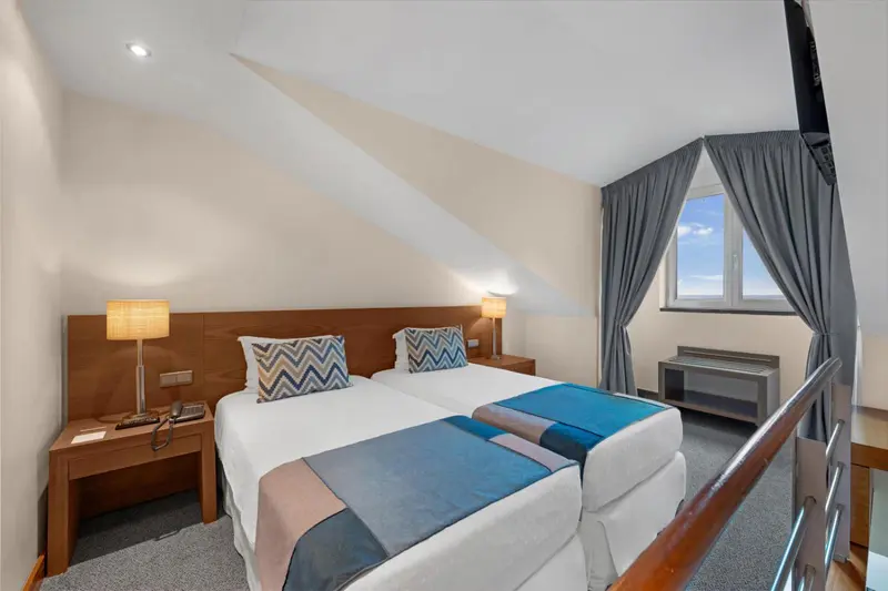 Une chambre lumineuse avec deux lits simples et une fenêtre.
